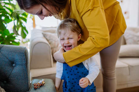 Mother consoling her little crying daughter at home.