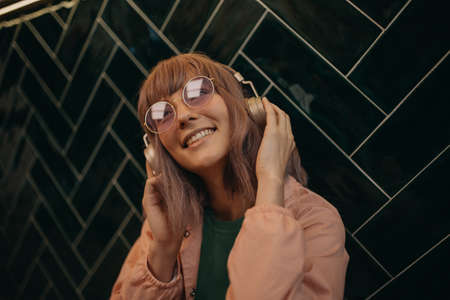 Young woman wearing headphones and enjoying listening to music indoors.