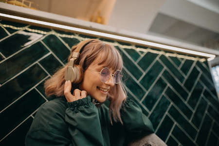 Young woman wearing headphones and enjoying listening to music indoors.の写真素材