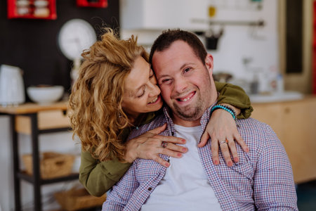 Portrait of mother hugging her grown up son with Down syndrome, motherhood concept.