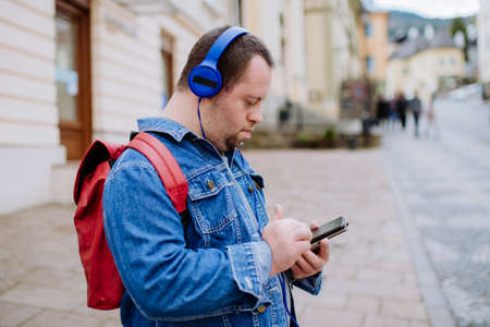 Happy young man with Down sydrome listening to music when walking in street.の写真素材