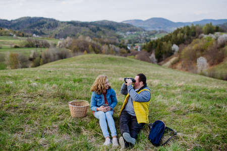 Happy young man with Down syndrome with his mother resting in nature, sitting and looking with binoculars.の写真素材