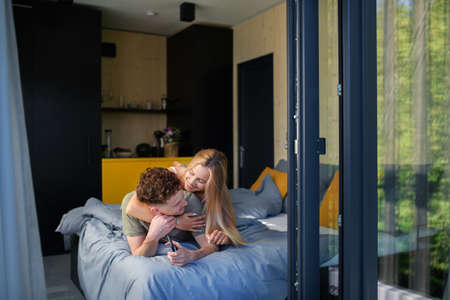 Young happy couple in love lying in bed in morning in their new home in tiny house,sustainable...