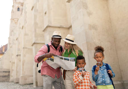 Multiracial family travel together in old city centre, looking at map.の写真素材