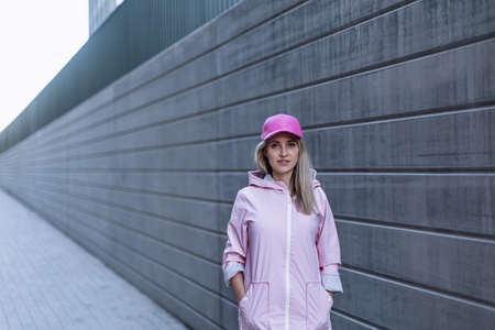Young woman in fashion clothes standing in city concrete wall.の写真素材