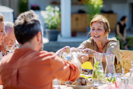 Multi generation family having garden party celebration, grandmother giving salad to her son.の写真素材