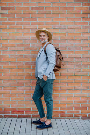 Portrait of confident man wearing straw hat and backpack looking at camera, businessman in casual clothes in summer on the way to work.の写真素材