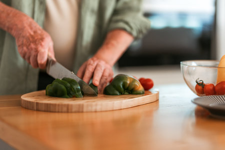 Close-up of senior man preparing vegetable, cutting at wooden board, healthy lifestyle concept.の写真素材