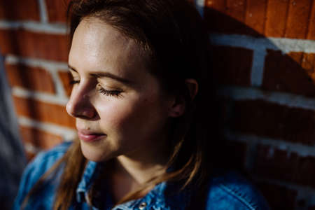 Portrait of happy young woman resting with closed eyes at home.の写真素材
