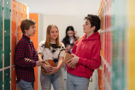 Young high school students meeting and greeting near locker in campus hallway, back to school concept.の写真素材