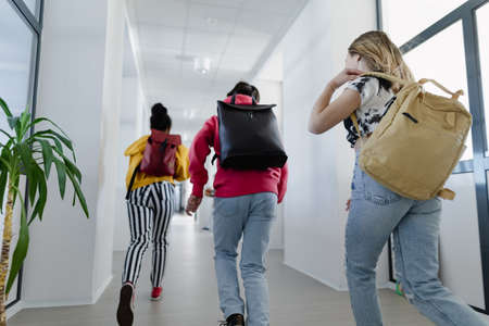 Rear view of young high school students walking in corridor at school, back to school concept.