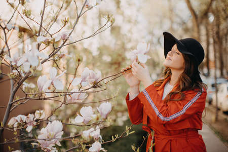 Portrait of beautiful young woman with blooming tree in spring in park.の写真素材