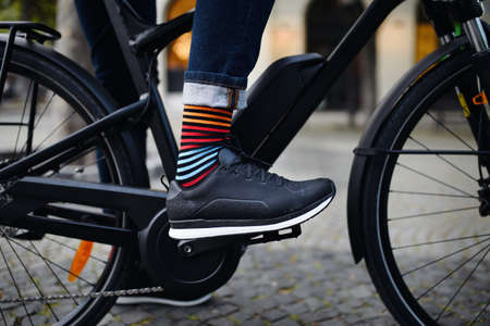 Businessman commuter on the way to work, close up of his legs riding bicycle.