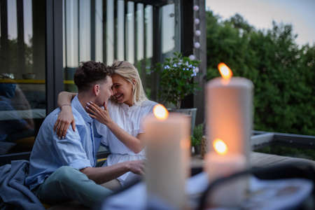 Young couple resting outdoors on terrace of tiny house in evening, weekend away in tiny house in...