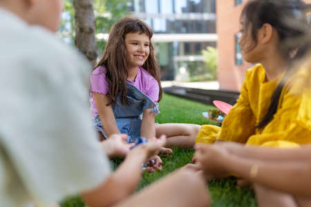 Happy kids playing and talking together in city park, during summer day.