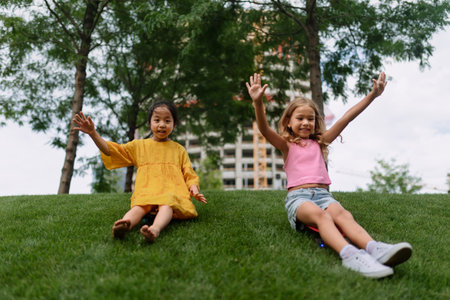 Asian girl trying to skateboarding with her friend in city park, active kids concept.の写真素材