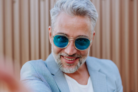 Portrait of successful happy businessman wearing causal clothes and sunglasses in summer in street...