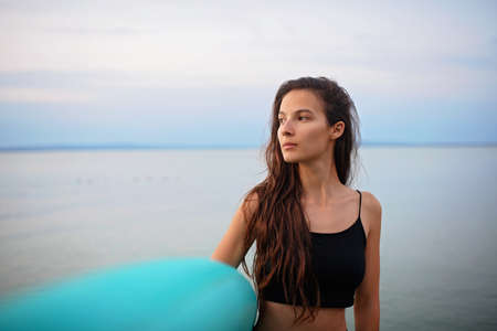 Young beautiful sportive girl with paddleboard on the lake at sunrise