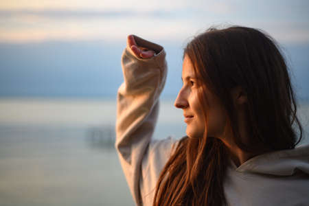 Young beautiful sportive girl looking at view at sunrise by the lake.
