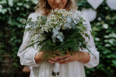 Close-up ofwedding bouquet in brides hands at reception outside in backyardの写真素材