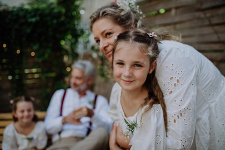 Mature bride and groom receiving congratulations from their little daughters at wedding reception...