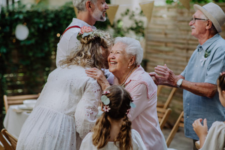 Mature bride and groom receiving congratulations at wedding reception outside in the backyard.の写真素材