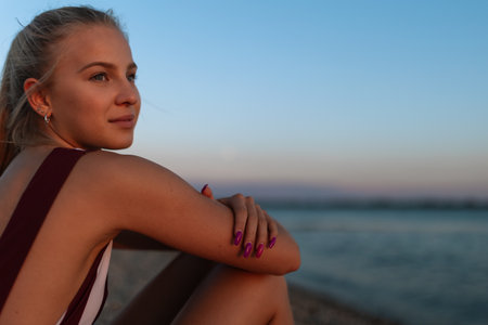 Young woman in swimsuit sitting on beach alone, summer vacation concept.の写真素材