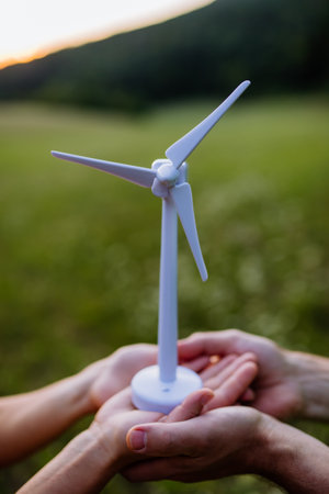 Close up of couple standing in nature with model of wind turbine. Concept of ecology future and renewable resources.の写真素材