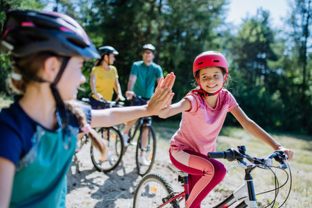 Young family with little children preapring for bike ride, standing with bicycles in nature and high fiving.の写真素材