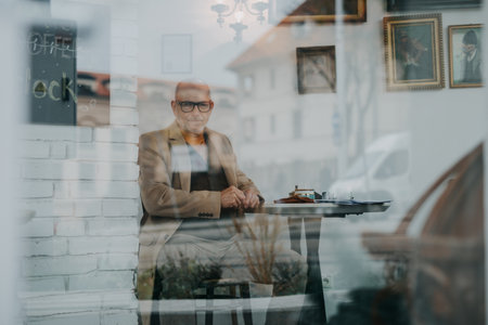 Elegant senior man sitting in a cafe and looking at camera.の写真素材