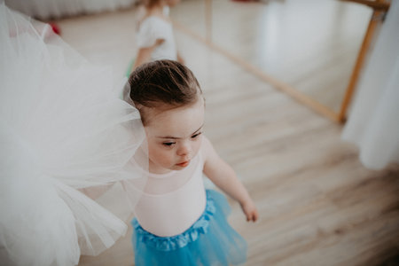 High angle view of little girl with down syndrome at ballet class in dance studio. Concept of integration and education of disabled children.の写真素材