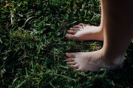 Close-up of barefoot legs standing in grass. Concept of healthy feet.の写真素材