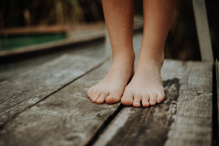 Close-up of barefoot legs standing on wooden pier. Concept of healthy feet.
