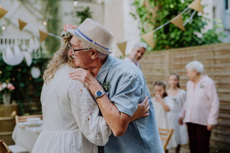 Mature bride receiving congratulations at wedding reception outside in the backyard.の写真素材