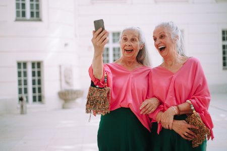 Senior women twins outdoors in city taking selfie.の写真素材