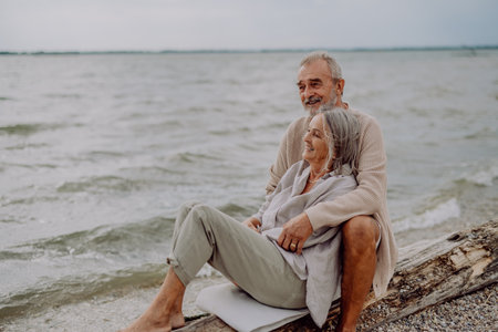 Senior couple sitting and having romantic moment near the autumn sea.の写真素材