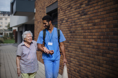 Happy caregiver caming back from grocery with his senior woman client.の写真素材
