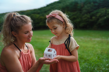 Little girl with her dad holding paper model of house with solar panels.Alternative energy, saving resources and sustainable lifestyle concept.の写真素材