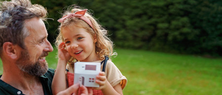 Little girl with her dad holding paper model of house with solar panels.Alternative energy, saving resources and sustainable lifestyle concept.の写真素材