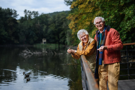 Happy senior couple at autumn walk near the lake, having break.の写真素材