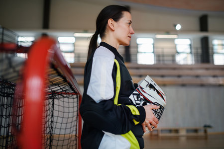 Close-up of woman floorball goalkeeper in helmet concetrating on game in gym.の写真素材