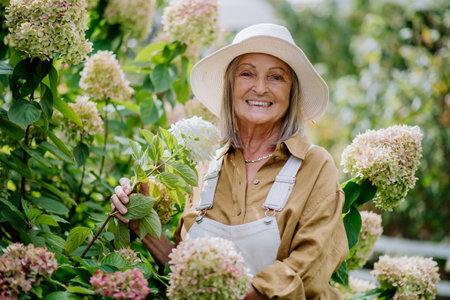 Happy senior woman posing in the flower garden.の写真素材