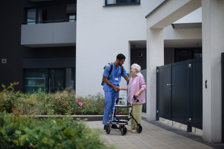 Caregiver walking with senior woman client in front of nurishing home.の写真素材