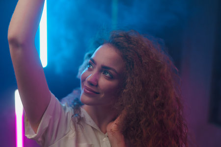 Portrait of a happy young woman dancing over neon light background at disco party