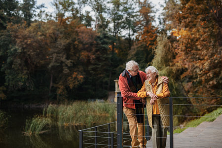 Happy senior couple at autumn walk near the lake, having break.