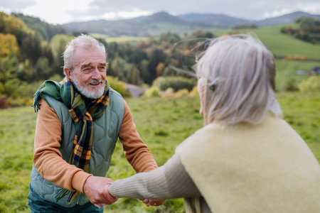 Happy senior couple walking in autumn meadow.の写真素材