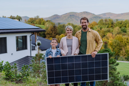 Happy family near their house with solar panel. Alternative energy, saving resources and sustainable lifestyle concept.の写真素材
