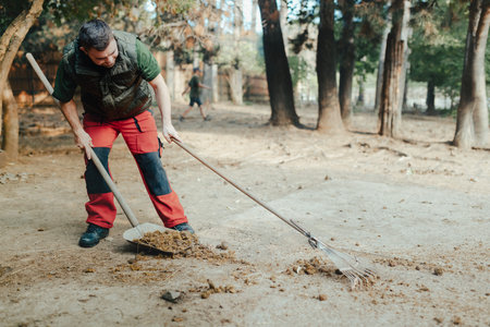 Caretaker with down syndrome in zoo cleaning animal enclosure. Concept of integration people with disabilities into society.の写真素材
