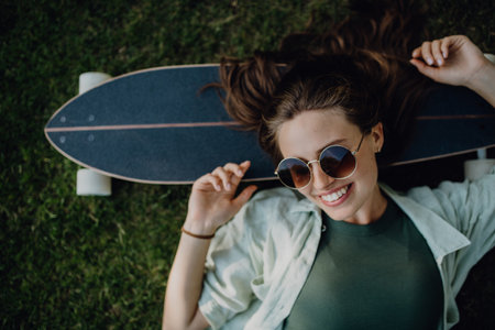 Top view of young woman lying on the grass with her skateboard.の写真素材