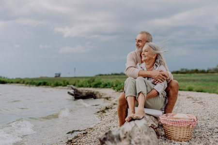 Senior couple sitting and having romantic moment near the autumn sea.の写真素材